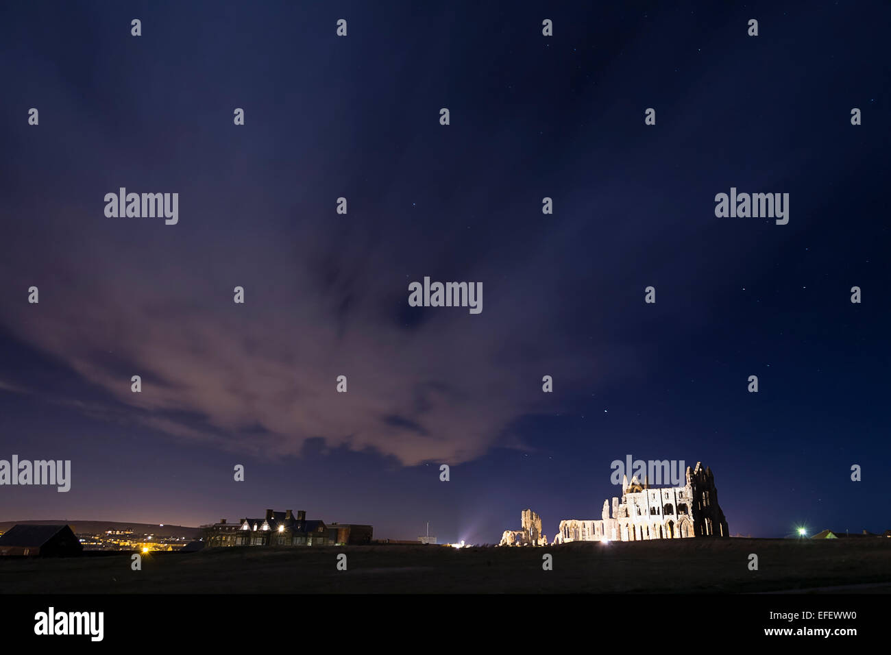 Fotografia paesaggio di Whitby Abbey scattata di notte, che mostra un cielo stellato con qualche nuvola. Foto Stock
