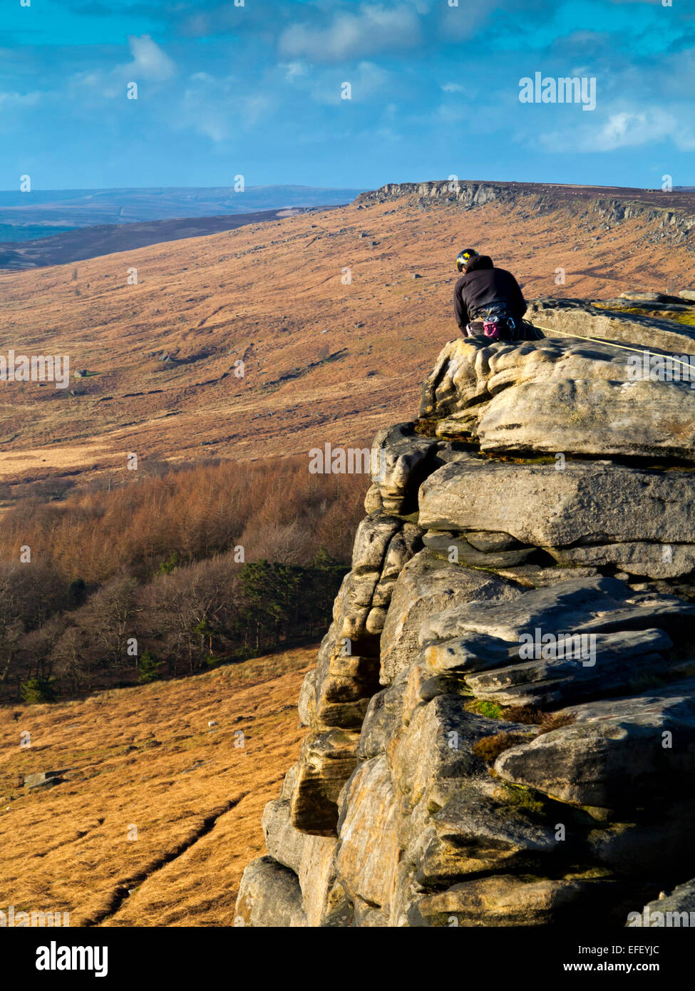 Scalatore circa a scendere una ripida scogliera faccia su rocce al bordo Stanage Parco Nazionale di Peak District DERBYSHIRE REGNO UNITO Foto Stock