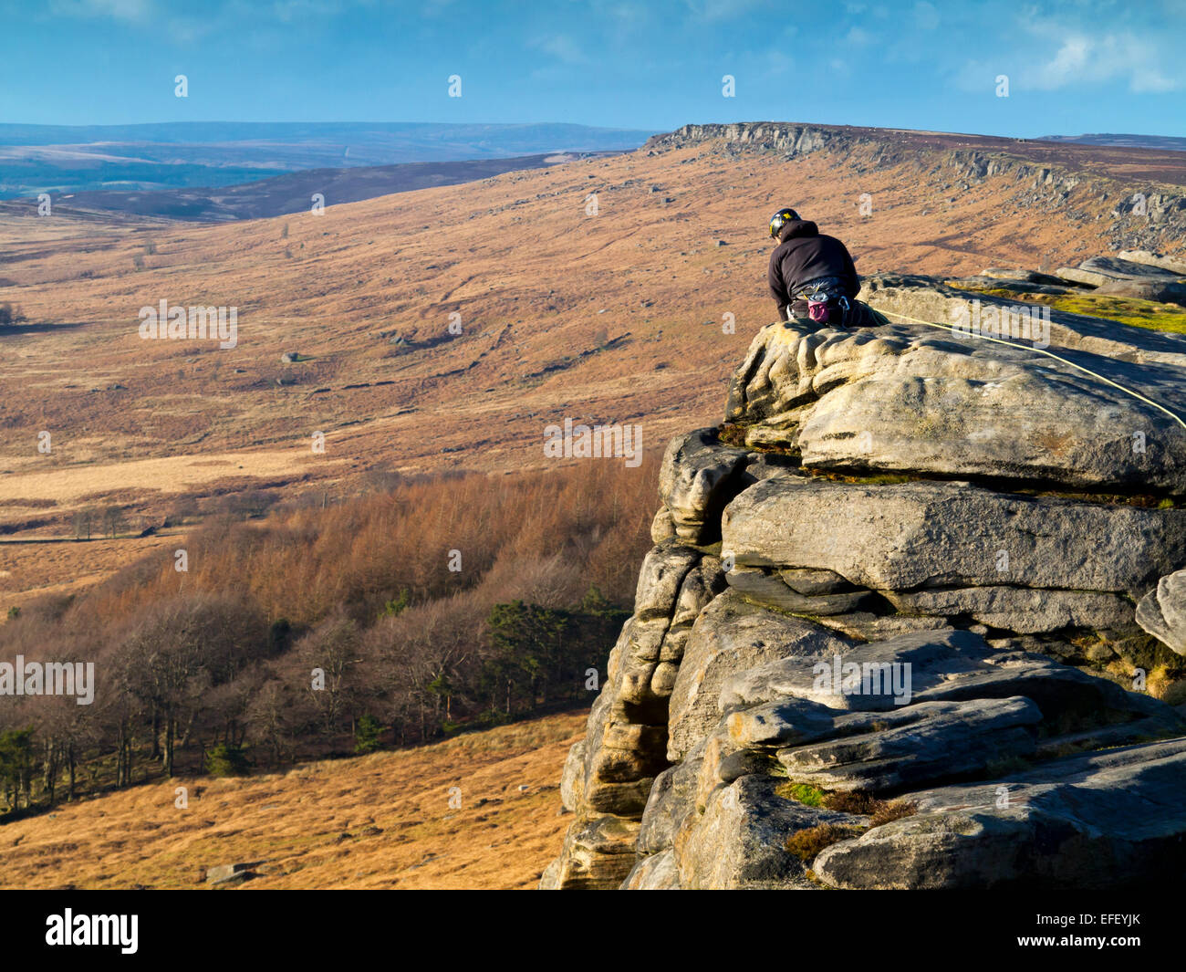 Scalatore circa a scendere una ripida scogliera faccia su rocce al bordo Stanage Parco Nazionale di Peak District DERBYSHIRE REGNO UNITO Foto Stock