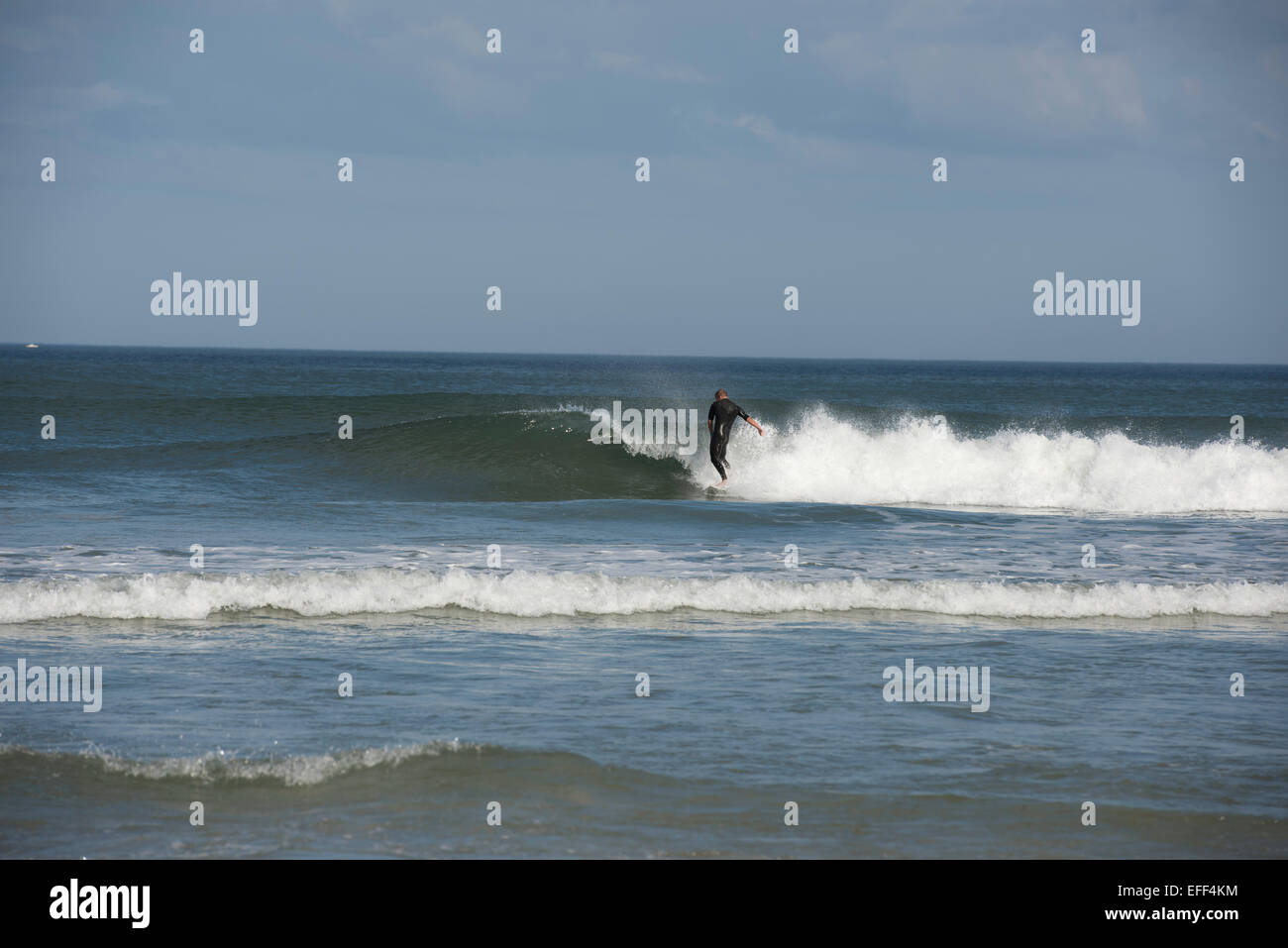 Un maschio di lone surfer indossando un nero muta a cavallo di un onda di rottura nell'Oceano Atlantico vicino a Daytona Beach, Florida, Stati Uniti d'America. Foto Stock