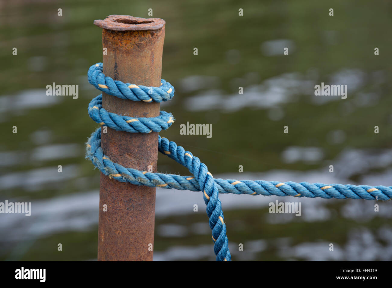 Nautica blu nodo corda allacciate intorno al palo arrugginito dall'acqua. Foto Stock