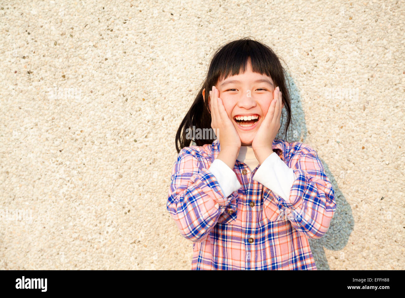Felice bambina davanti alla parete Foto Stock