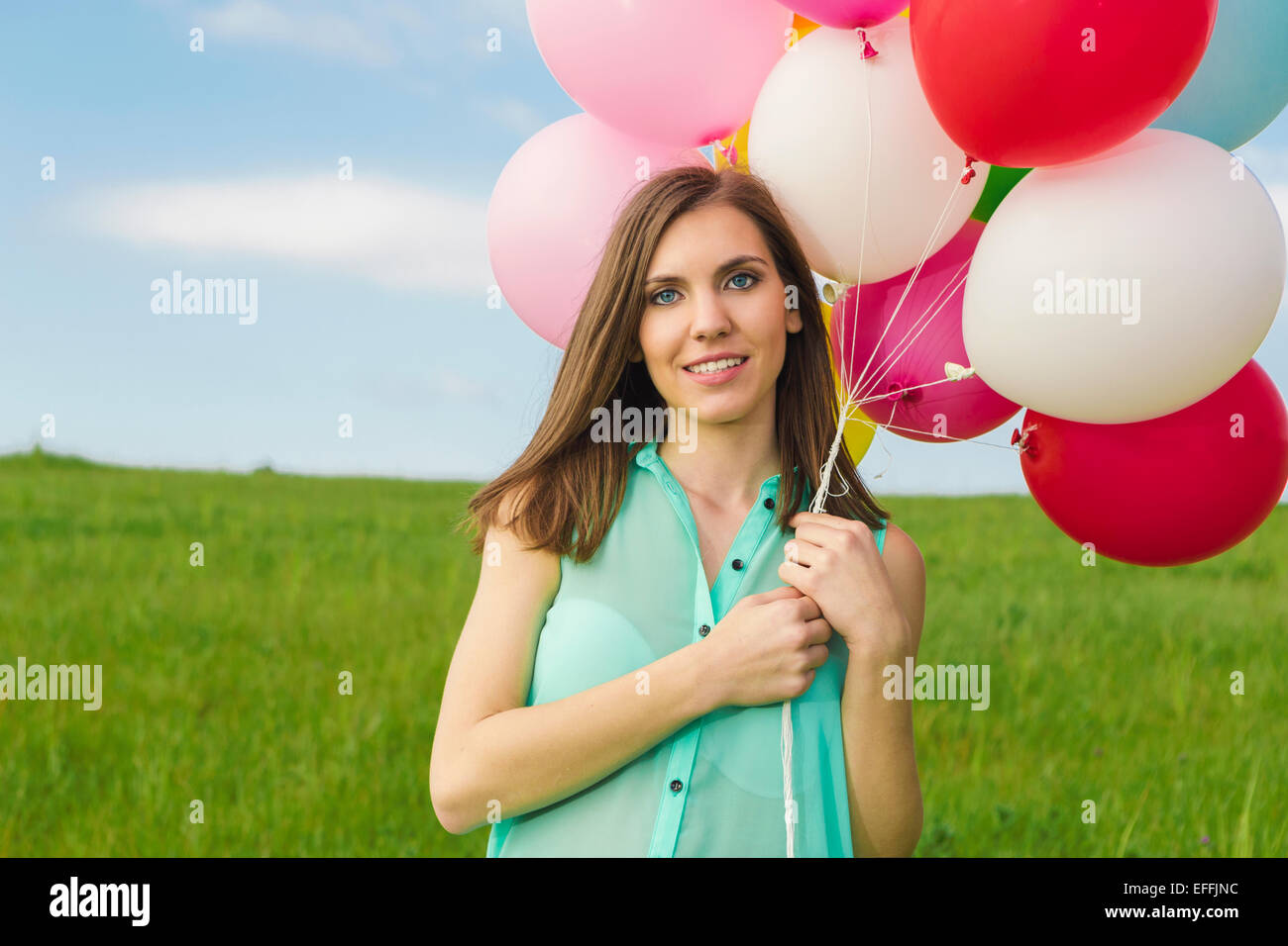 Giovane donna bella avendo divertimento con palloncini su un verde prato Foto Stock