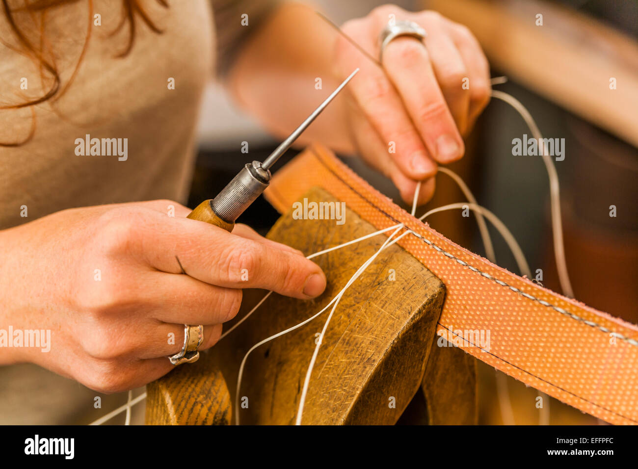 Donna di cucitura del tessuto elastico rubber band utilizzando i lacci pony e awl Foto Stock