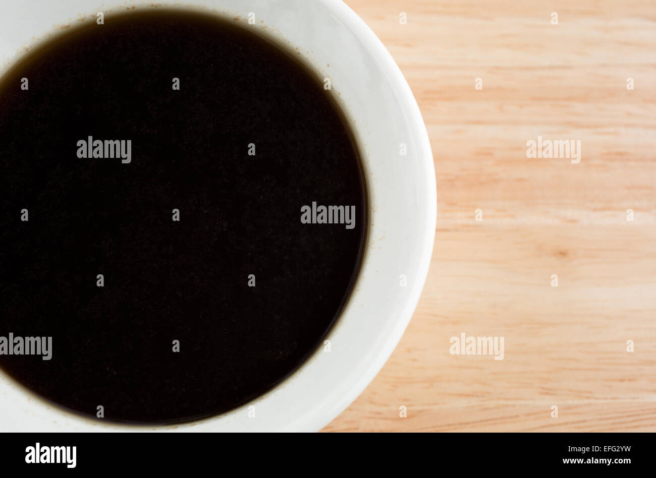 Una vista ravvicinata di una piccola ciotola di Au Jus salsa su una tavola di legno alto. Foto Stock