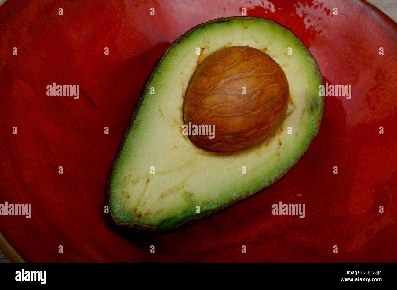 Dolce metà di avocado su un rosso coppa in ceramica Foto Stock