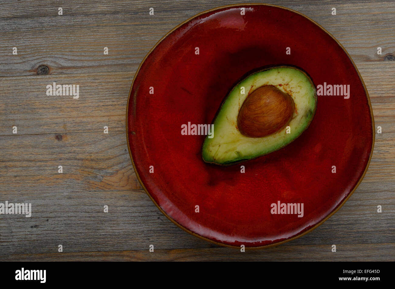 Metà di avocado su un rosso coppa in ceramica Foto Stock