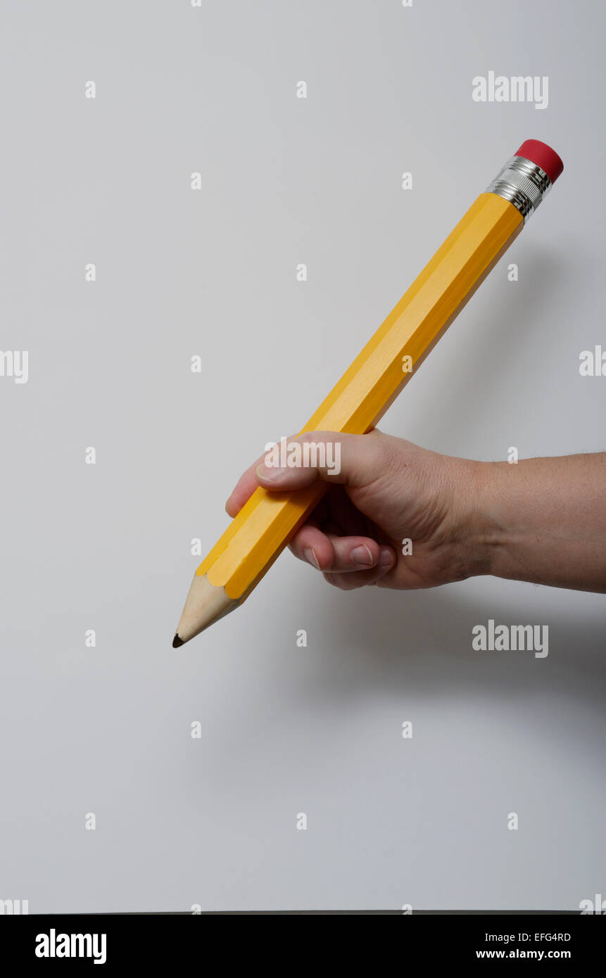 La mano di presa di una grande matita su sfondo neutro Foto Stock