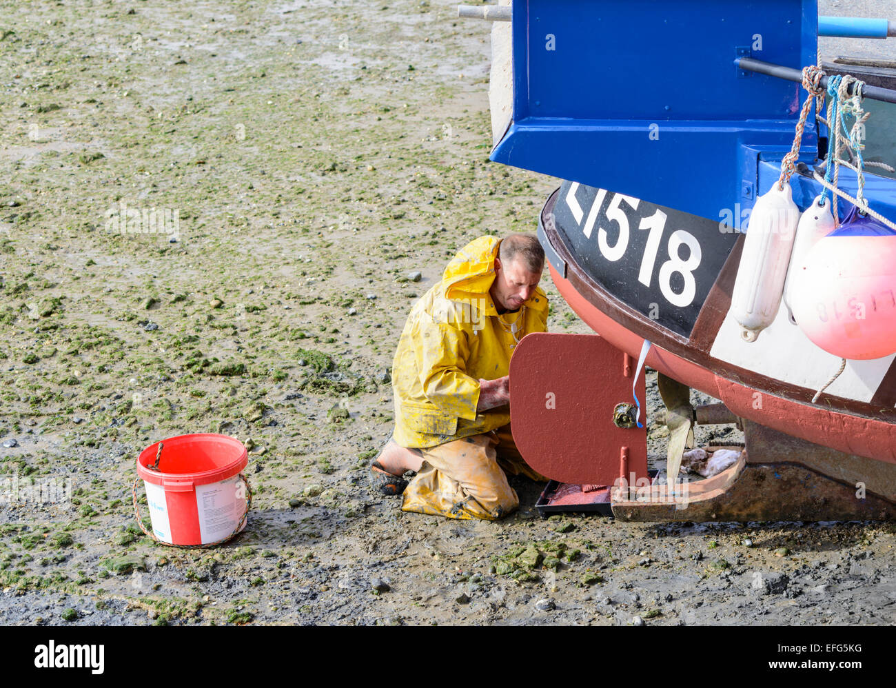 Uomo al lavoro su il timone di una barca al di fuori dell'acqua. Foto Stock