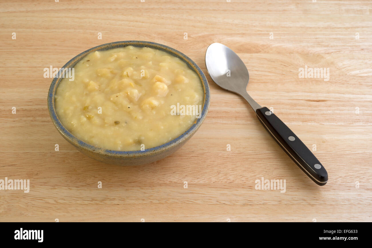 A che serve della fecola di patate e zuppa di porri in una ciotola con un manico nero cucchiaio per lato su una tavola di legno alto. Foto Stock