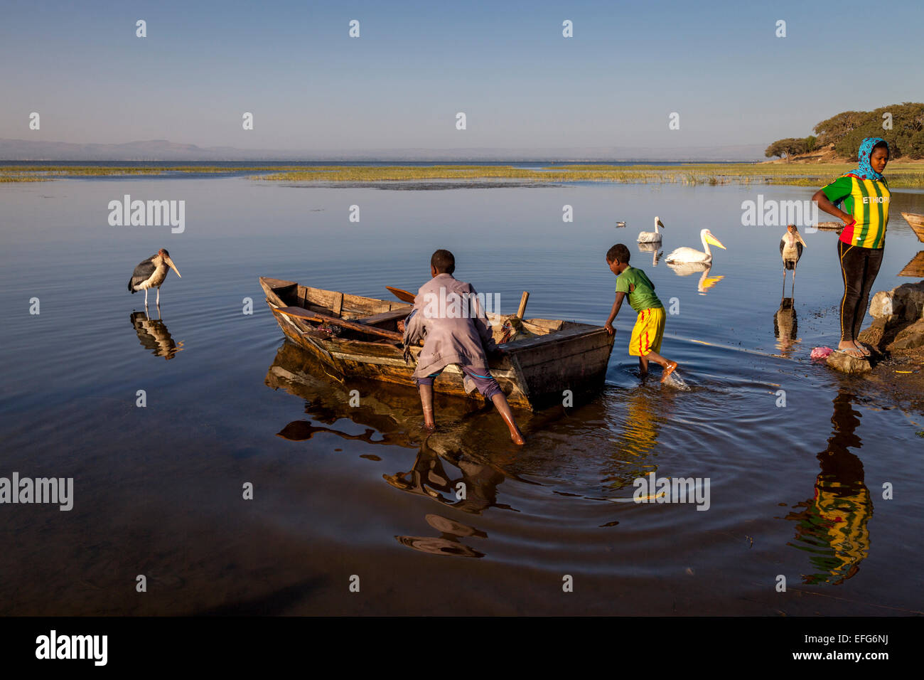 Due ragazzi spingendo fuori una barca da pesca, Lago Hawassa, Hawassa, Etiopia Foto Stock