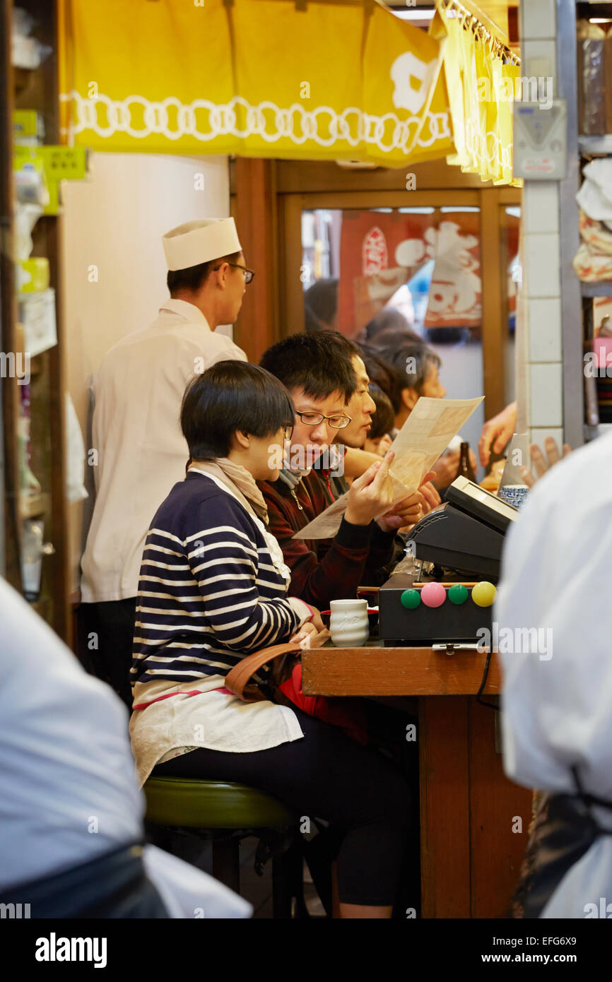 La gente nel ristorante di sushi guardando il menu , Mercato del pesce Tsukiji, mercato Tsukiji, Tokyo, Giappone Foto Stock