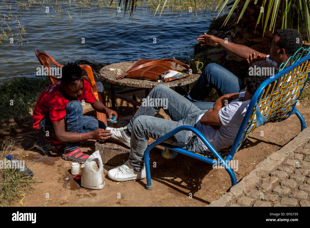 Un turista etiope ha le sue scarpe pulite da un Lustrascarpe Boy, Lago Hawassa, Hawassa, Etiopia Foto Stock