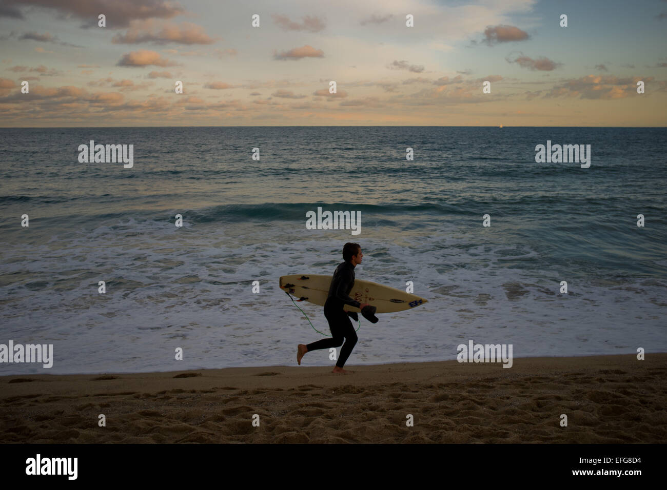 Barcellona, Spagna. 3 febbraio, 2015. Un surfista corre lungo la spiaggia di Barcellona come il sole tramonta dopo una pioggia e freddo giorno. Credito: Jordi Boixareu/Alamy Live News Foto Stock