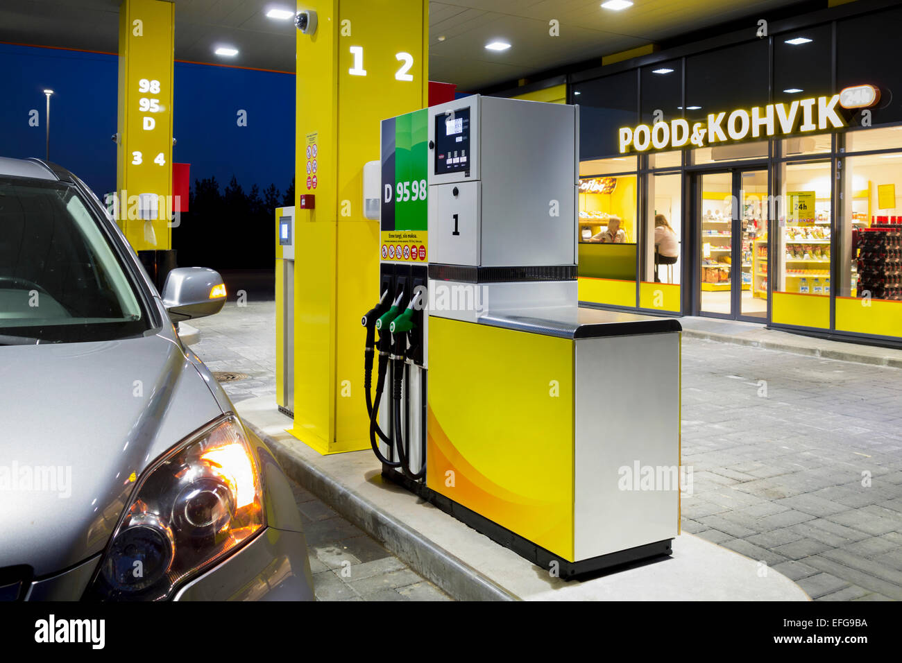 Auto in stazione di gas. Carburante, distributore di benzina, la pompa, maniglie e montanti. Il rifornimento di carburante. L'Estonia. Finestra illuminata di convenience store. Foto Stock