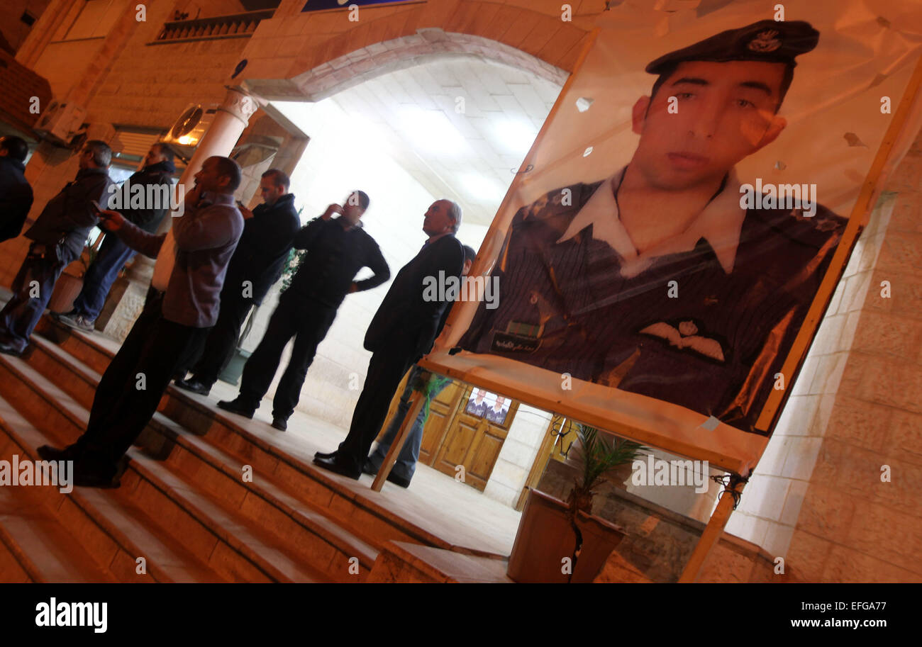 Amman, Giordania. 3 febbraio, 2015. Persone in stand by un poster del Giordano Moaz pilota al-Kasasbeh dopo il rilascio di un video che si asseriscono che mostra uno stato islamico captive Giordani essendo pilota bruciato vivo nel pilota della città natale Karak, Giordania, nel febbraio 3, 2015. Governo giordano martedì ha confermato l uccisione del pilota di giordani tenuto prigioniero da uno Stato islamico (SI), secondo membro-run Petra nuova agenzia. Credito: Mohammad Abu Ghosh/Xinhua/Alamy Live News Foto Stock