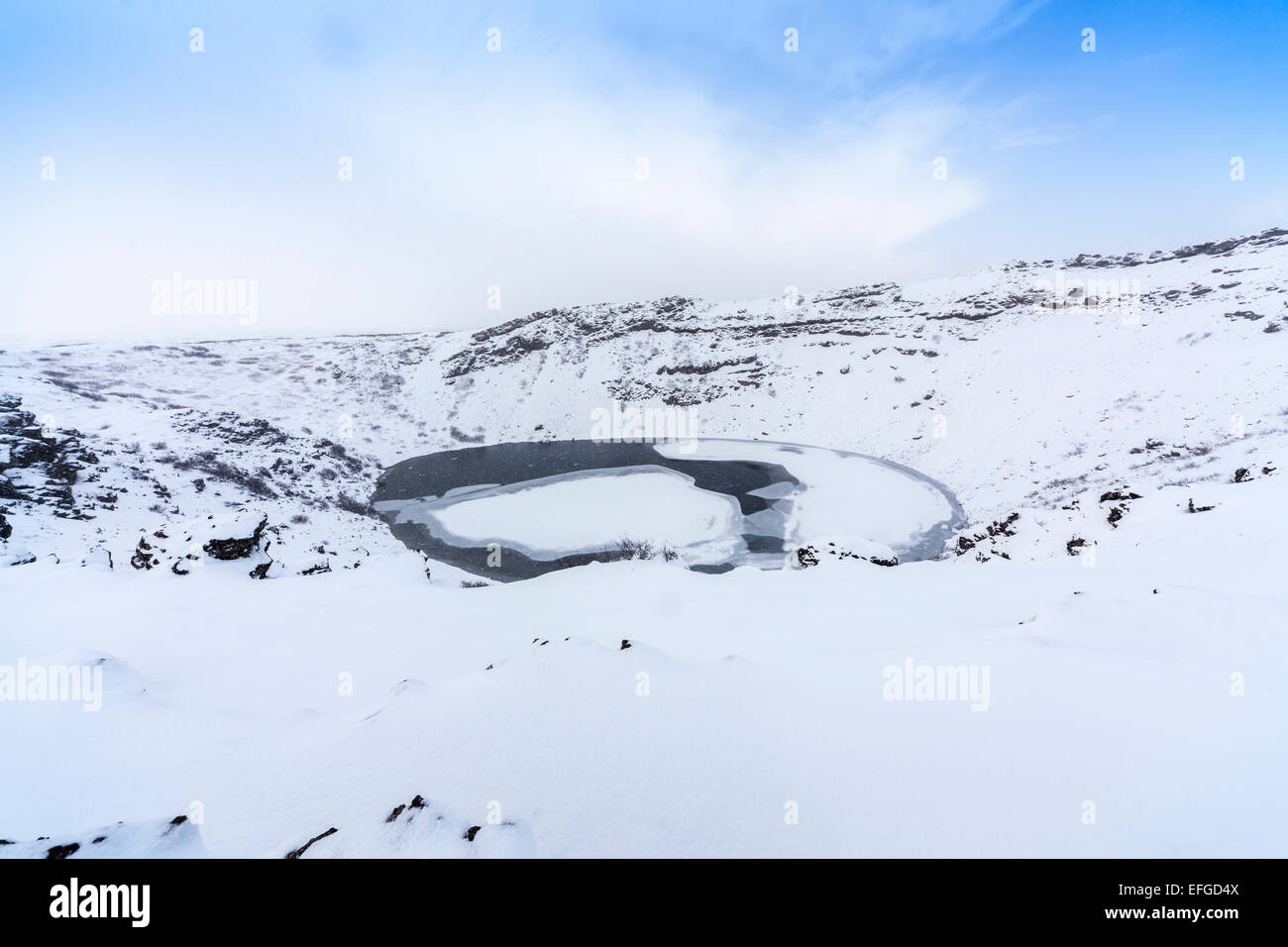 La caldera rocciose di Kerid (o) Kerith vulcano e congelato il cratere del lago in Islanda, una popolare destinazione turistica in inverno durante una nevicata Foto Stock