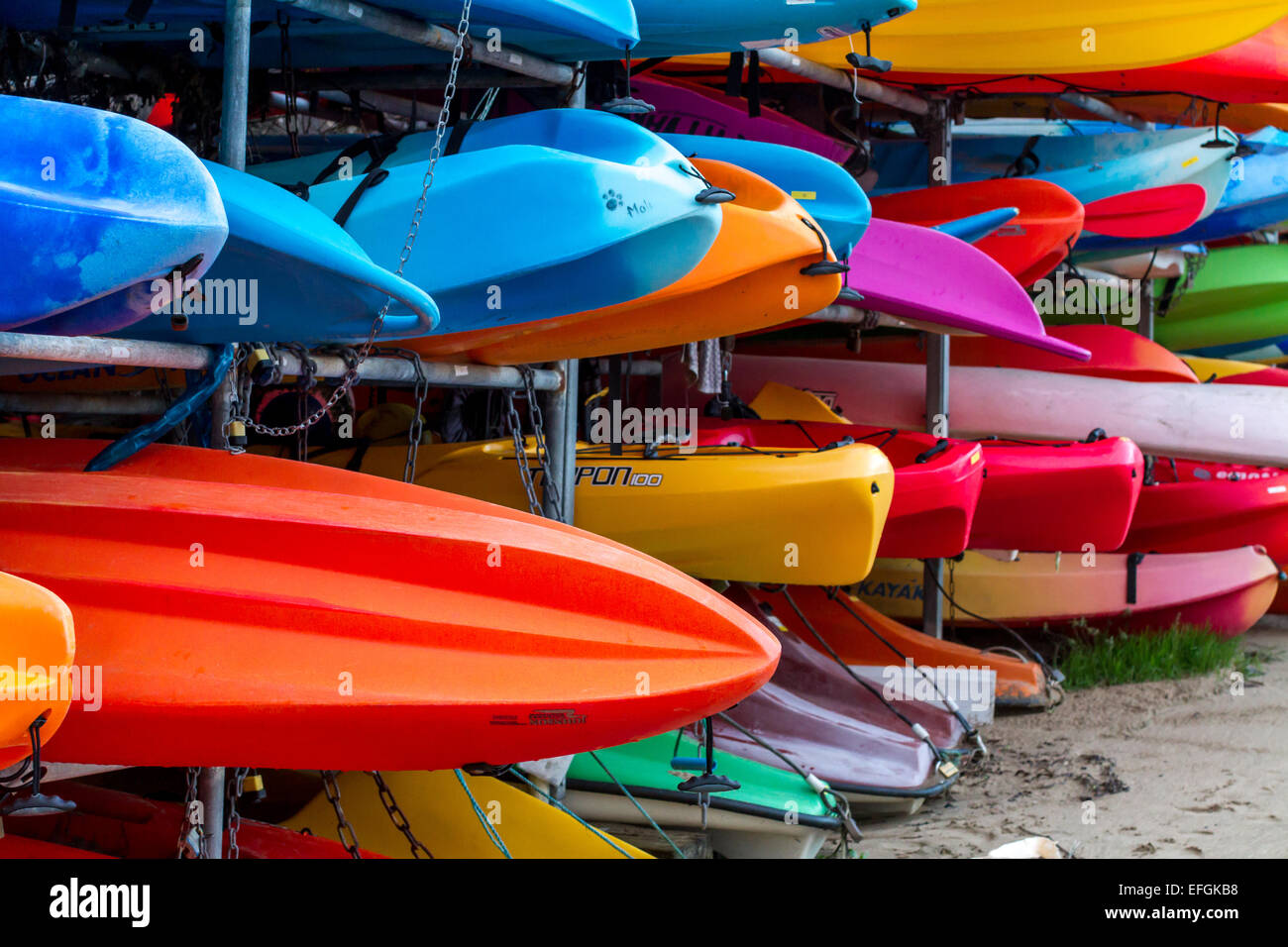 Vivacemente colorato kayak impilati su un rack pronto per l'uso. Foto Stock