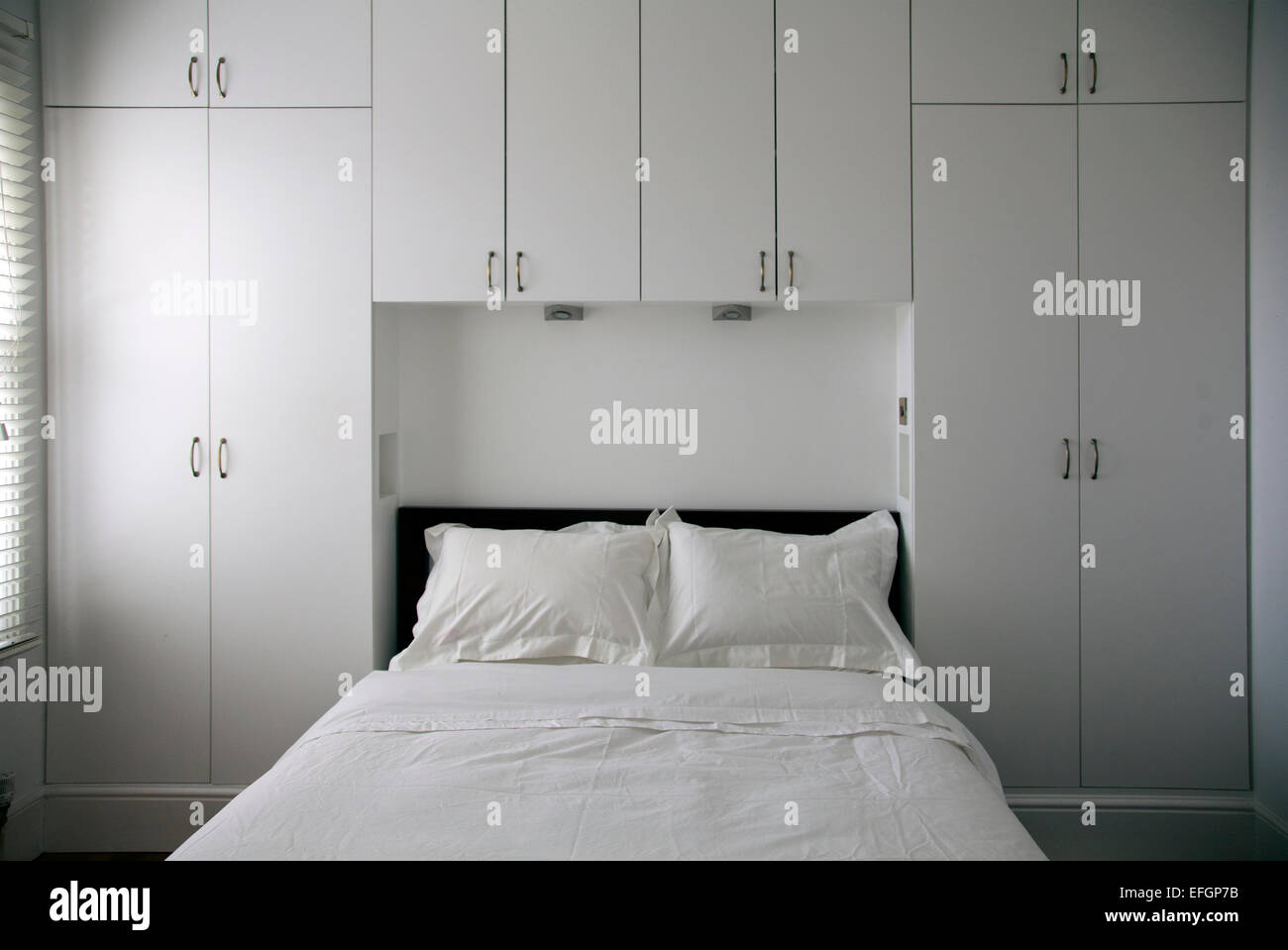 Interiore camera da letto con lenzuola bianche Foto Stock