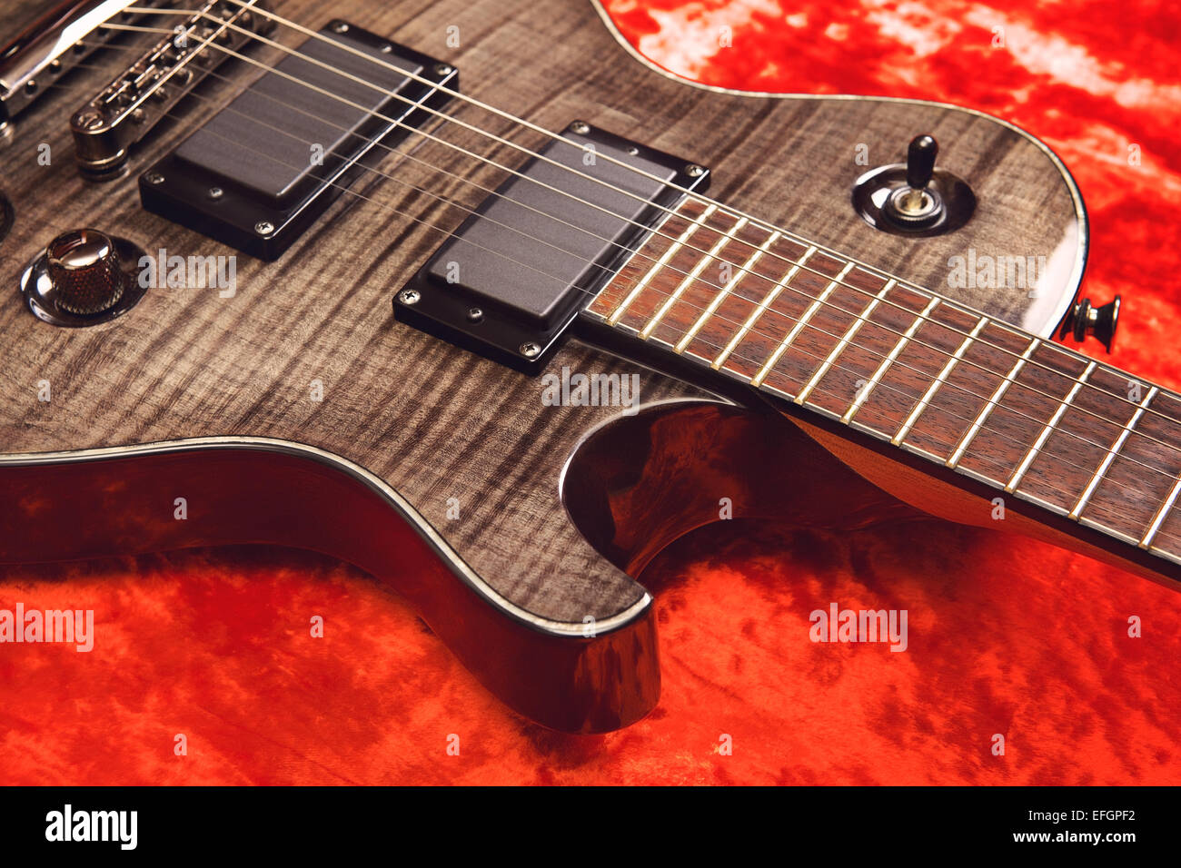 Nero chitarra elettrica sul velluto rosso sfondo Foto Stock