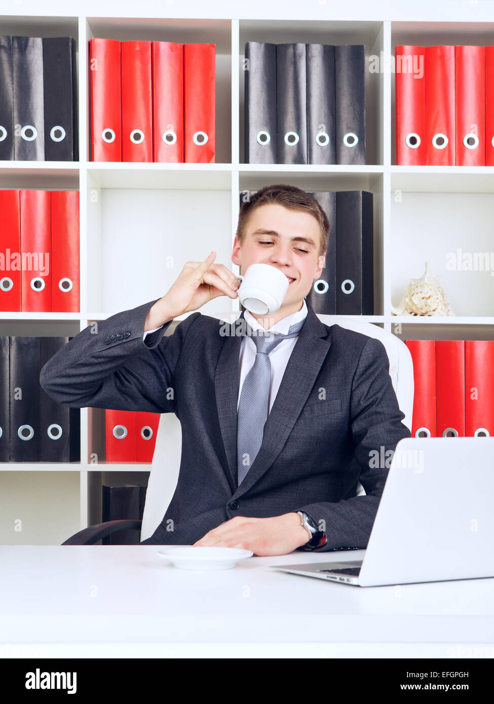 Successo imprenditore giovane bere il caffè nel suo ufficio Foto Stock