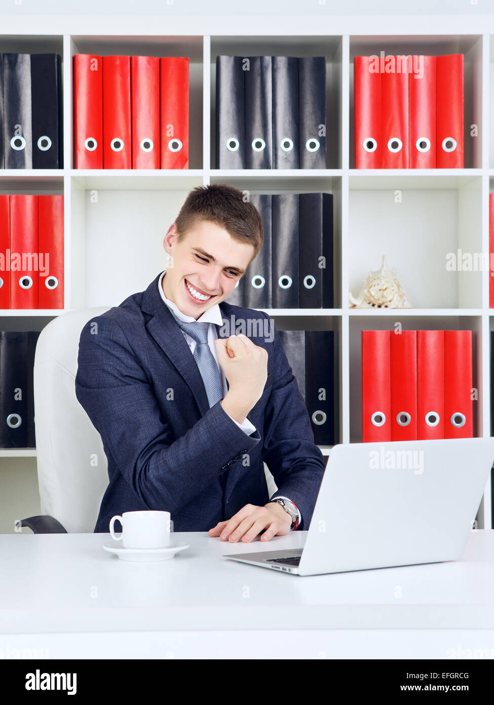 Fiducioso giovane impreditore trionfo guardando al laptop Foto Stock