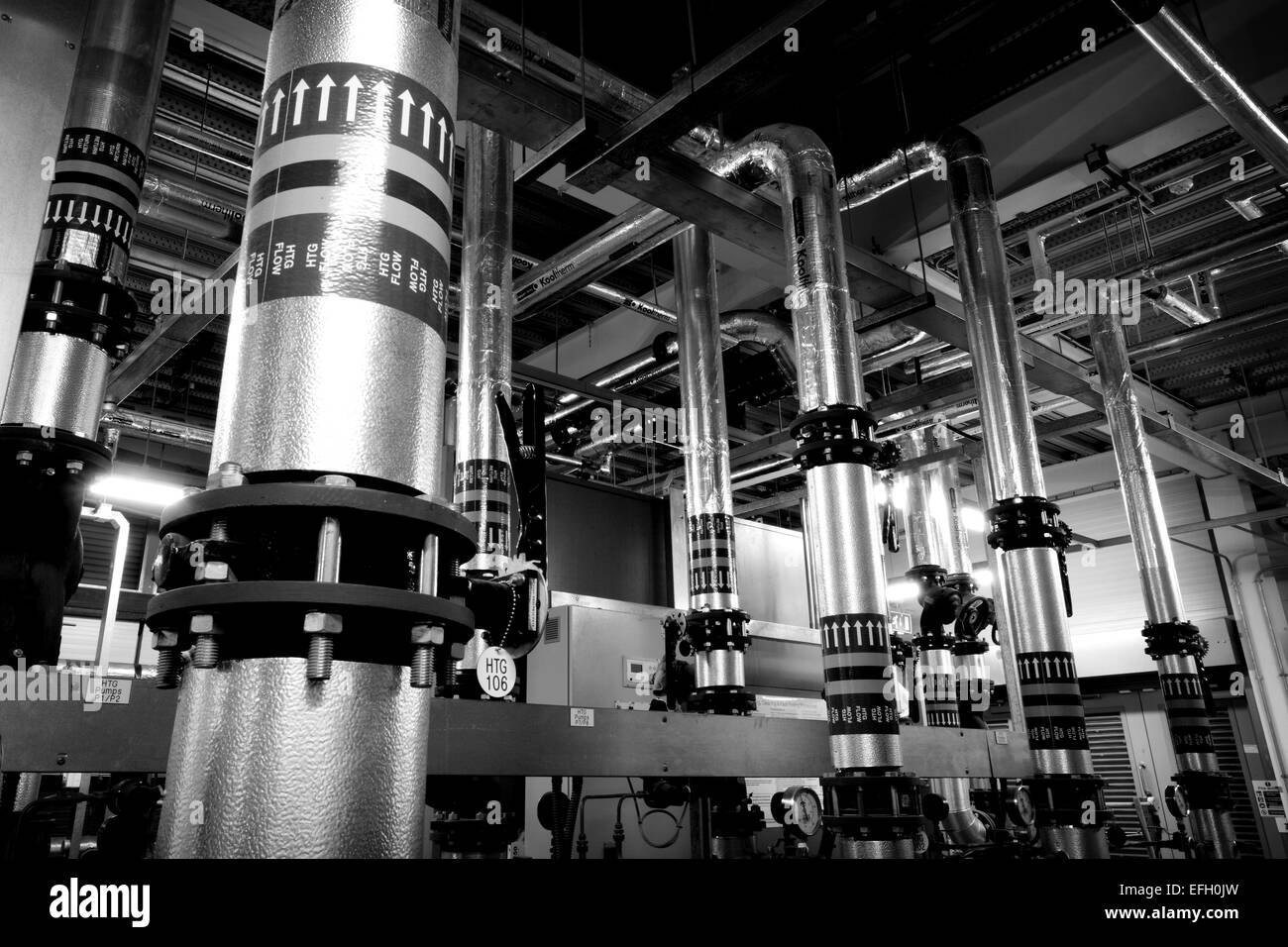Caldaia a biomassa e piping industriale in un impianto di biomasse, in bianco e nero Foto Stock