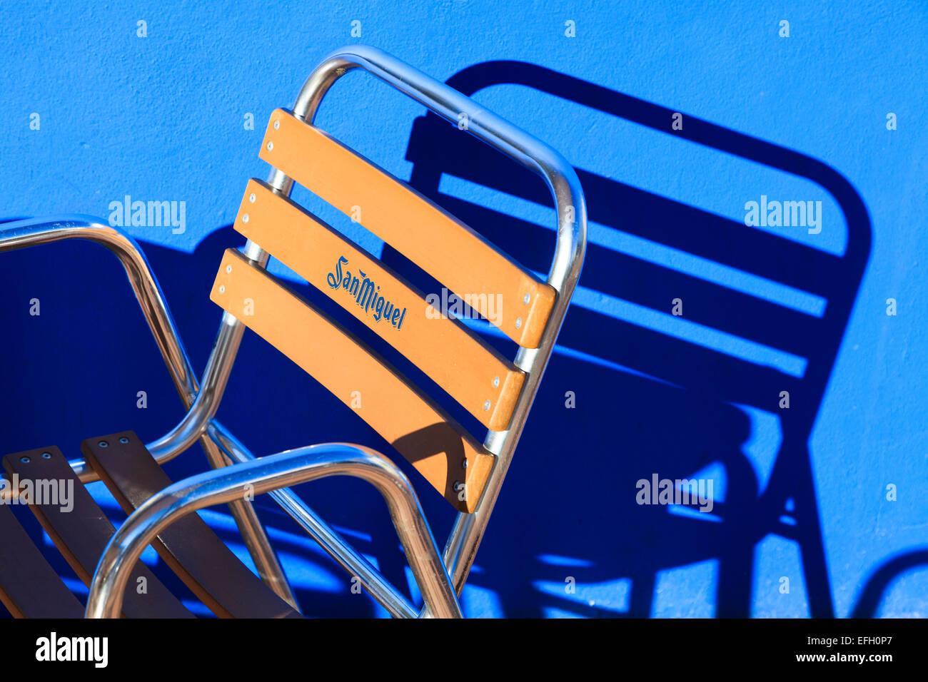 Una forte immagine di San Miguel di marca sedia frame di luce e di ombra di colata sulla parete blu Foto Stock