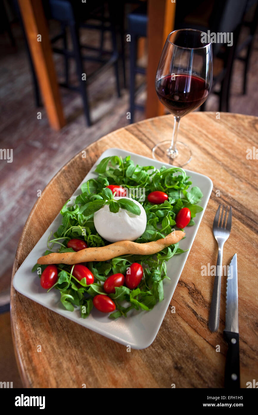 Mozzarella, insalata verde e un bicchiere di vino rosso in un pub Foto Stock