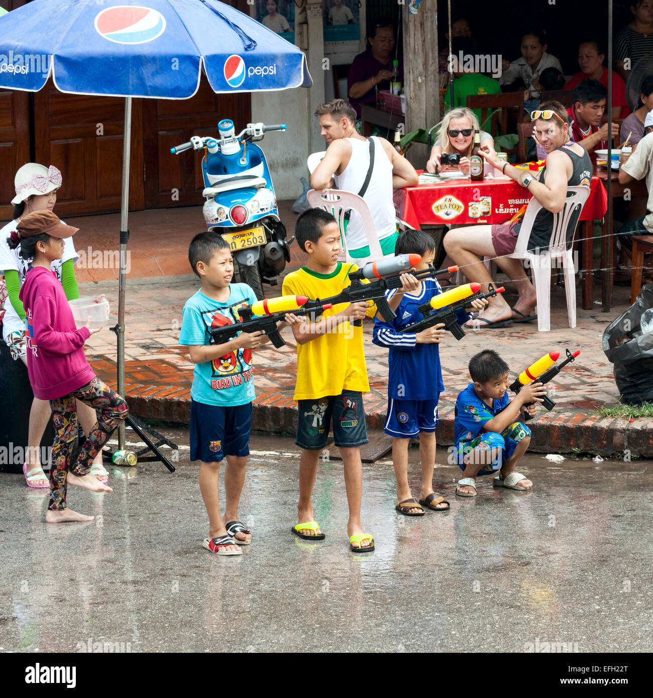 Ragazzi piccoli godere gli spruzzi di persone con pistola ad acqua durante la celebrazione del Lao Nuovo Anno e Festival dell'acqua a Luang Prabang. Foto Stock