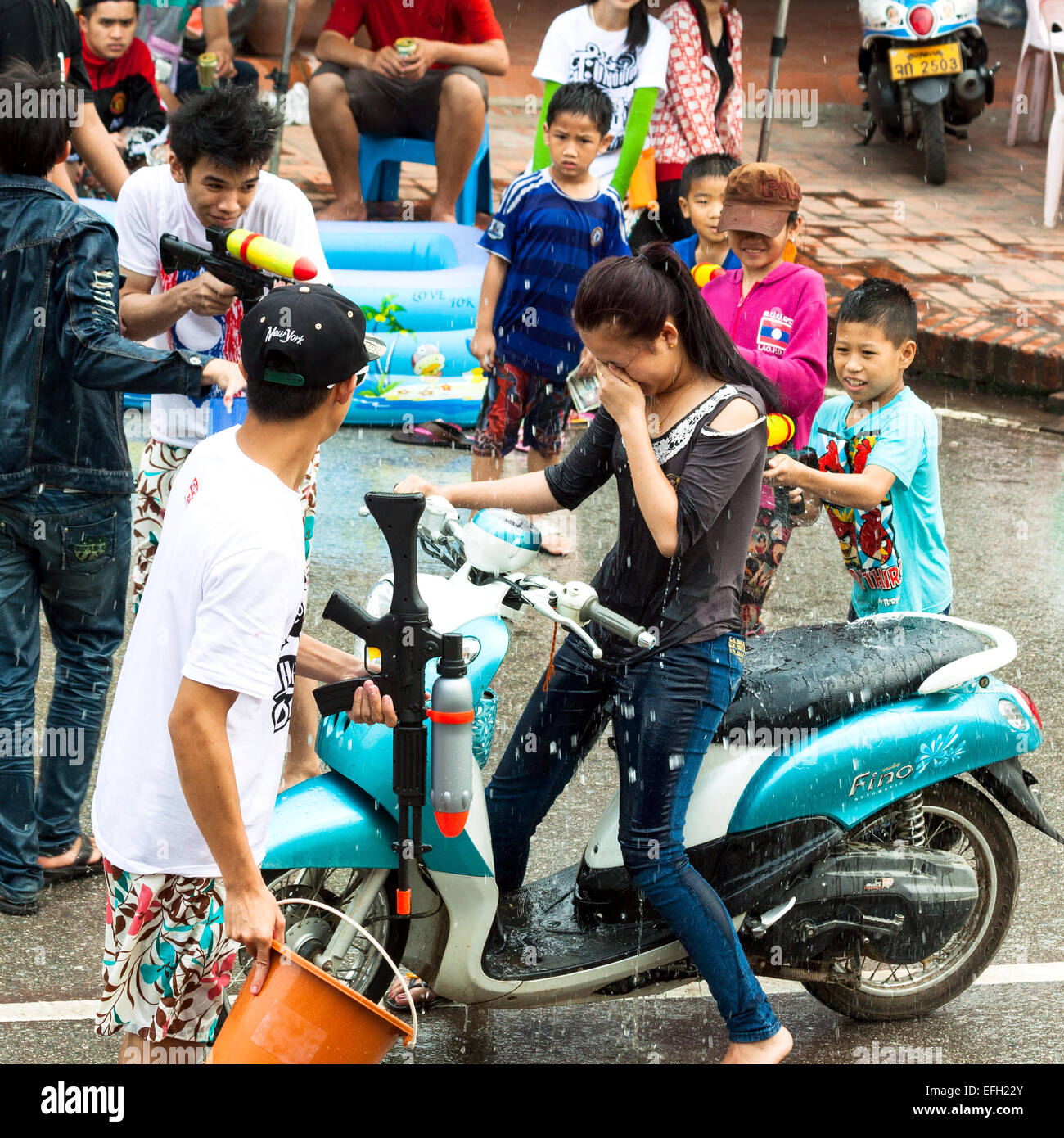 Ragazzi piccoli godere gli spruzzi di persone con pistola ad acqua durante la celebrazione del Lao Nuovo Anno e Festival dell'acqua a Luang Prabang. Foto Stock
