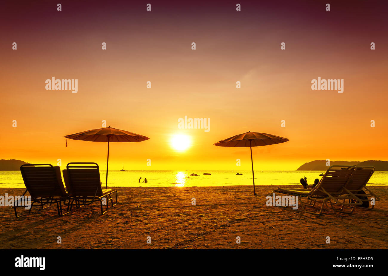 Retrò immagine filtrata di sedie a sdraio e ombrelloni sulla spiaggia al tramonto. Concetto per il riposo, il relax, vacanze. Foto Stock