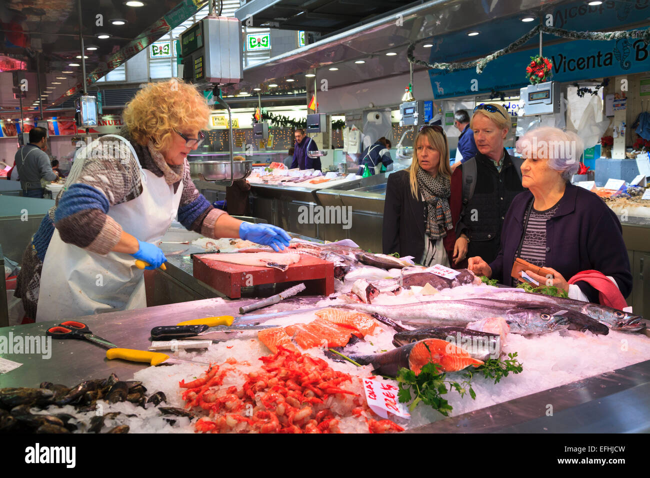 Commerciante di mercato la sfilettatura pesce per un cliente nel mercato centrale di Valencia Foto Stock