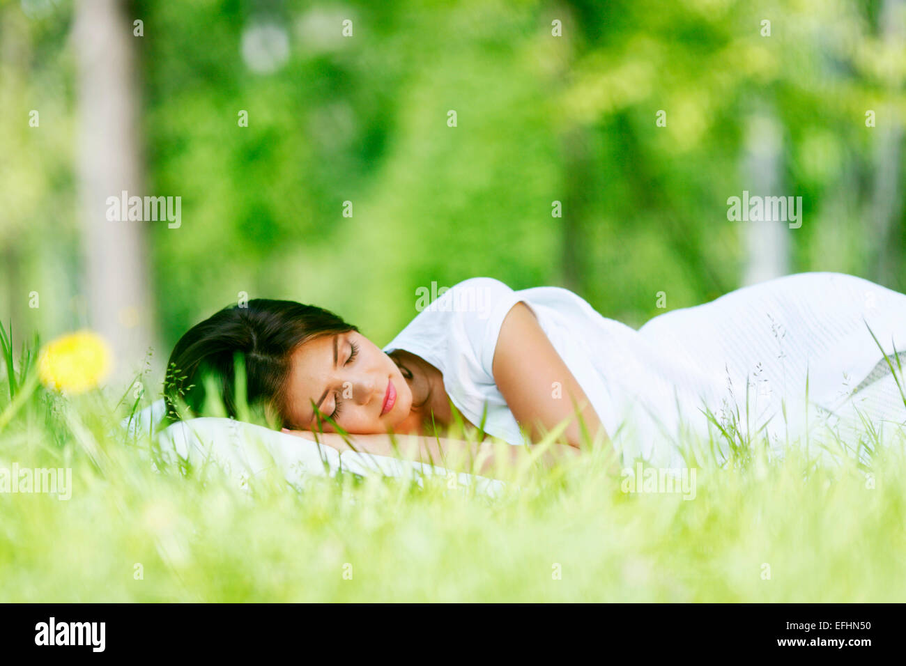 Giovane e bella donna che dorme su erba all'aperto Foto Stock