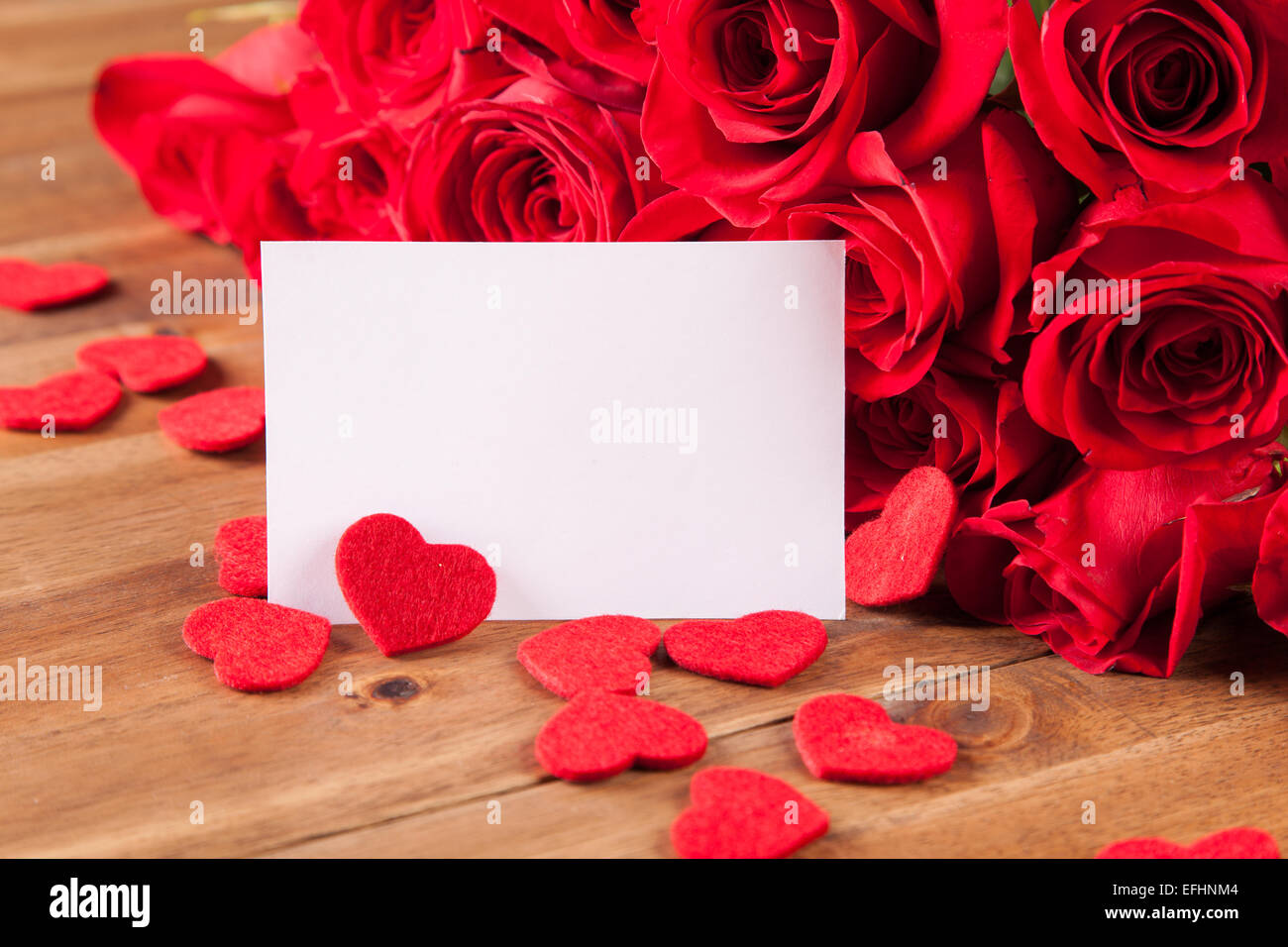 Bouquet di rose con fogli di carta bianca sulla scrivania in legno Foto Stock