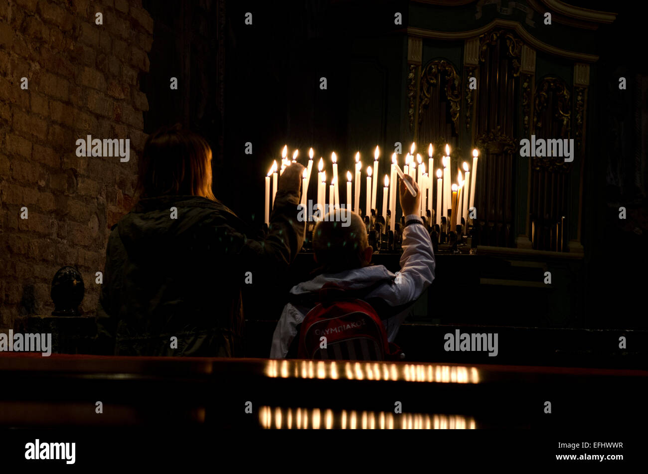 Madre e figlio accendendo candele in una chiesa di Venezia, Italia Foto Stock