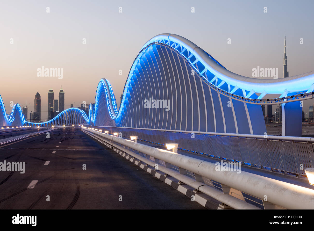 Forma d'onda Meydan ponte in Dubai blu illuminata di notte. Emirati Arabi Uniti Foto Stock