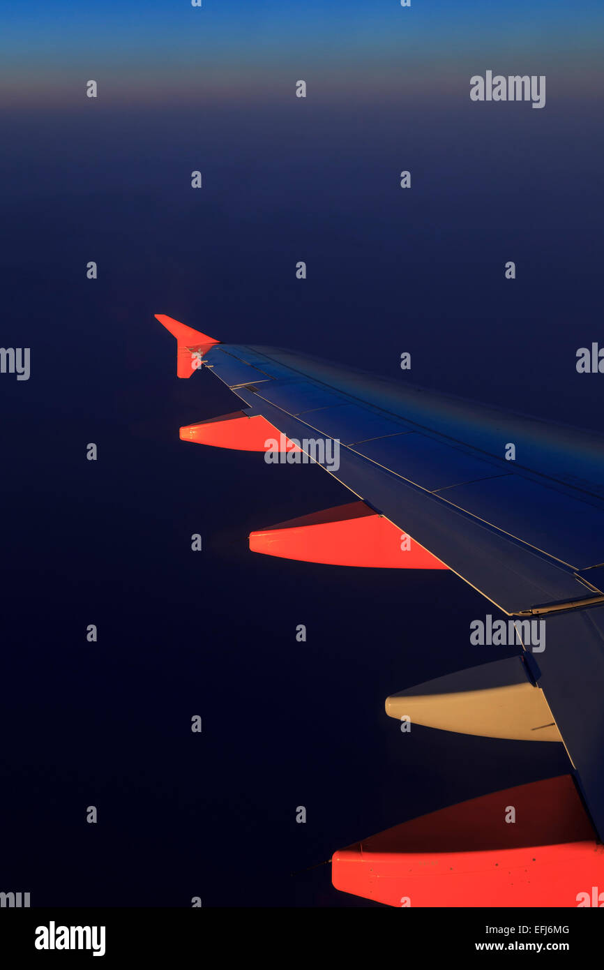 Ala di un aeroplano sopra le nuvole all'alba Foto Stock