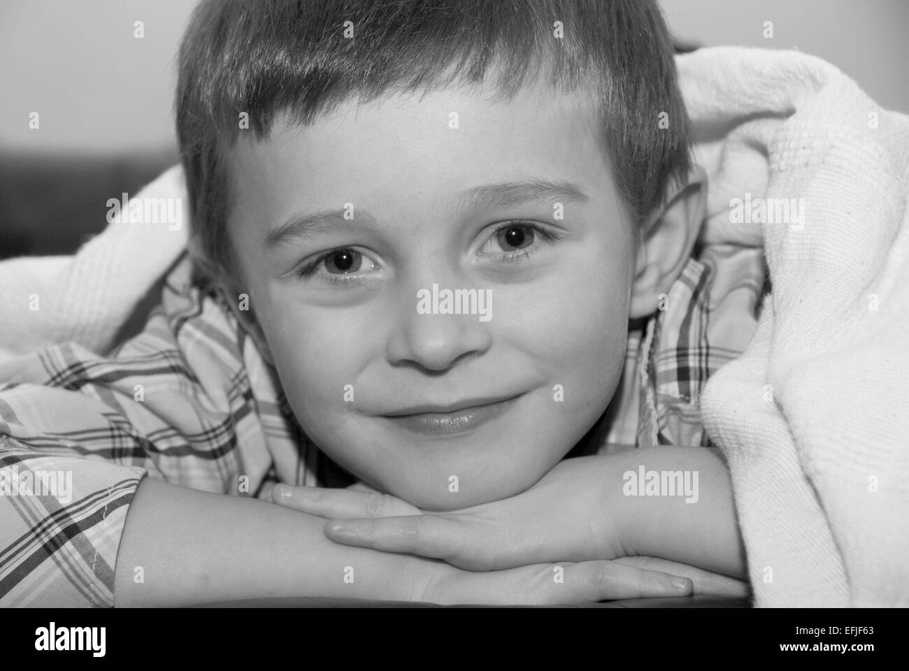 Ritratto in bianco e nero di un ragazzo con la testa sulle mani che giace sulla sua parte anteriore Foto Stock