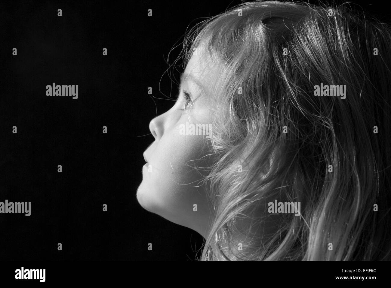Bianco e nero ritratto di una giovane ragazza di profilo, isolato su nero Foto Stock