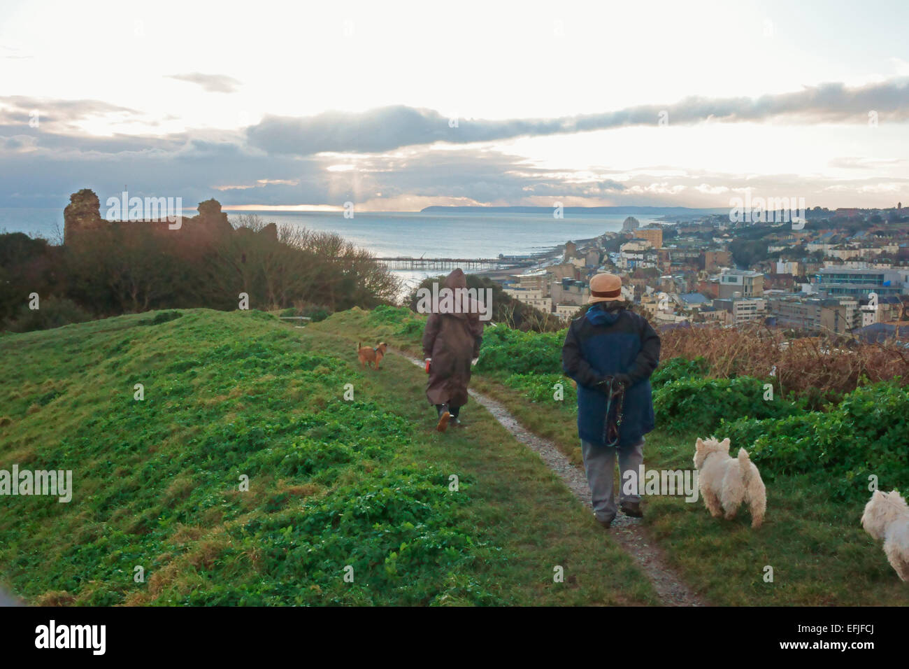 East Sussex, Hastings 5 Feb 2015. Dog walkers sulla Collina del Castello gli ultimi raggi di sole su una fredda sera sulla costa sud Foto Stock