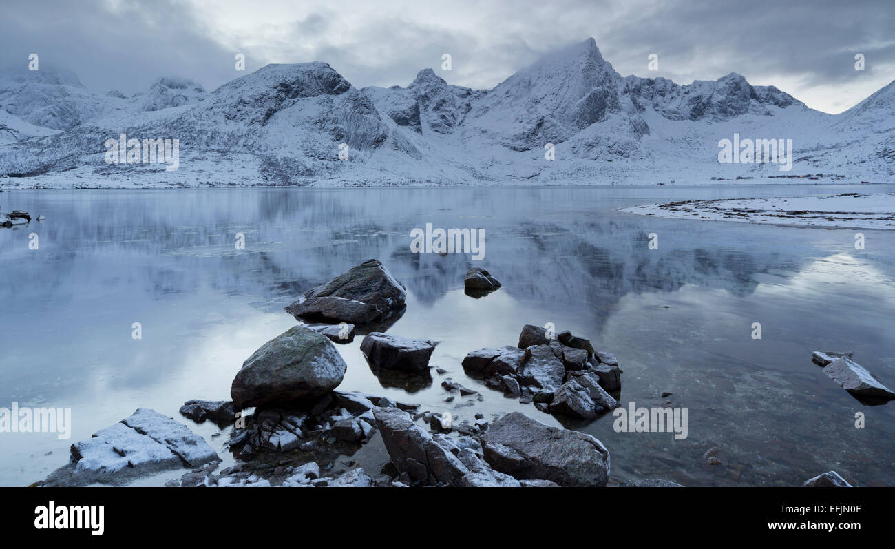Fiordo con la riflessione di montagne in acqua, Stortinden, Flakstadpollen, Flakstadoya, Lofoten, Nordland, Norvegia Foto Stock