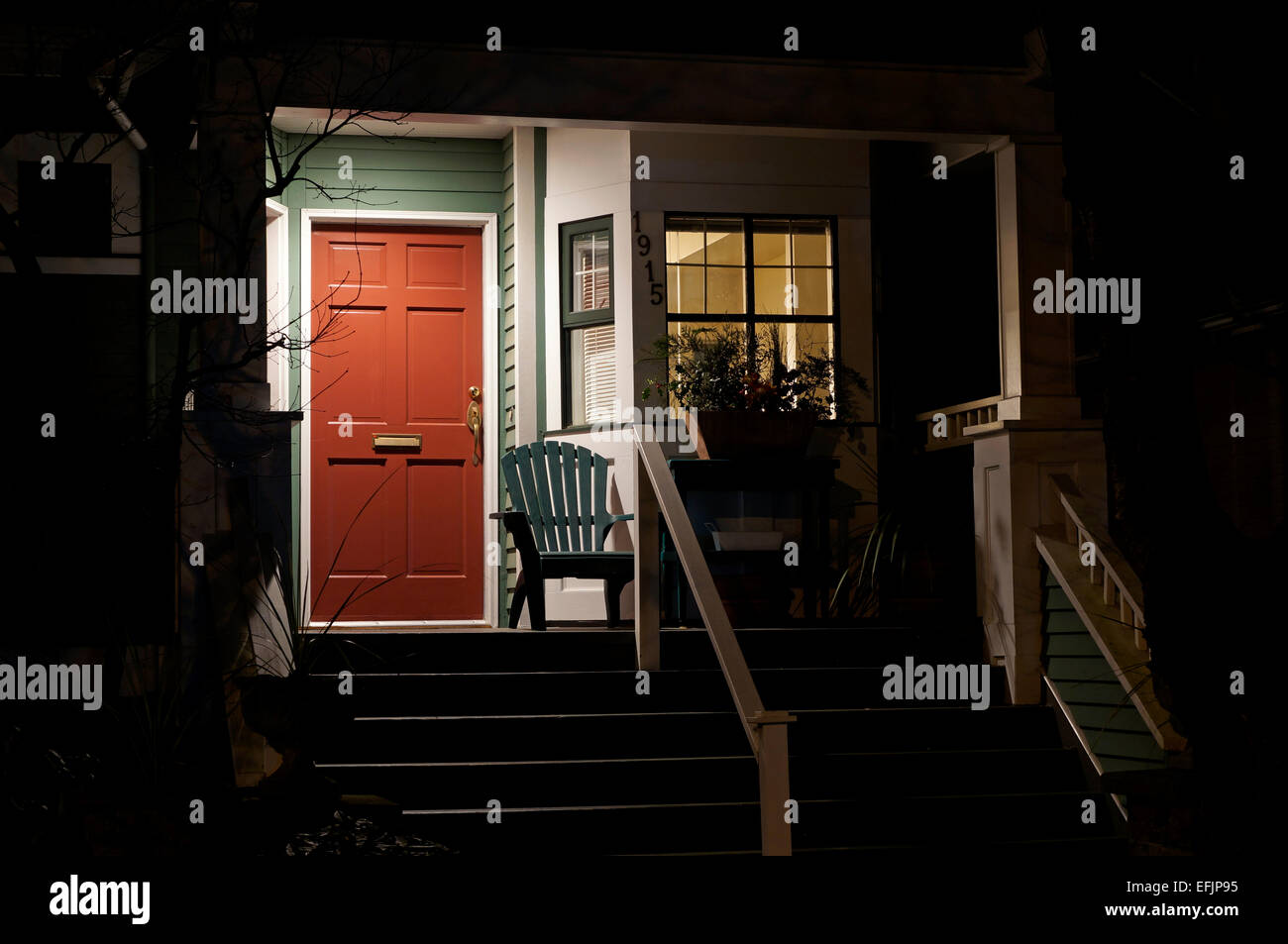 Portico frontale di una casa e il rosso porta di legno di notte Foto Stock