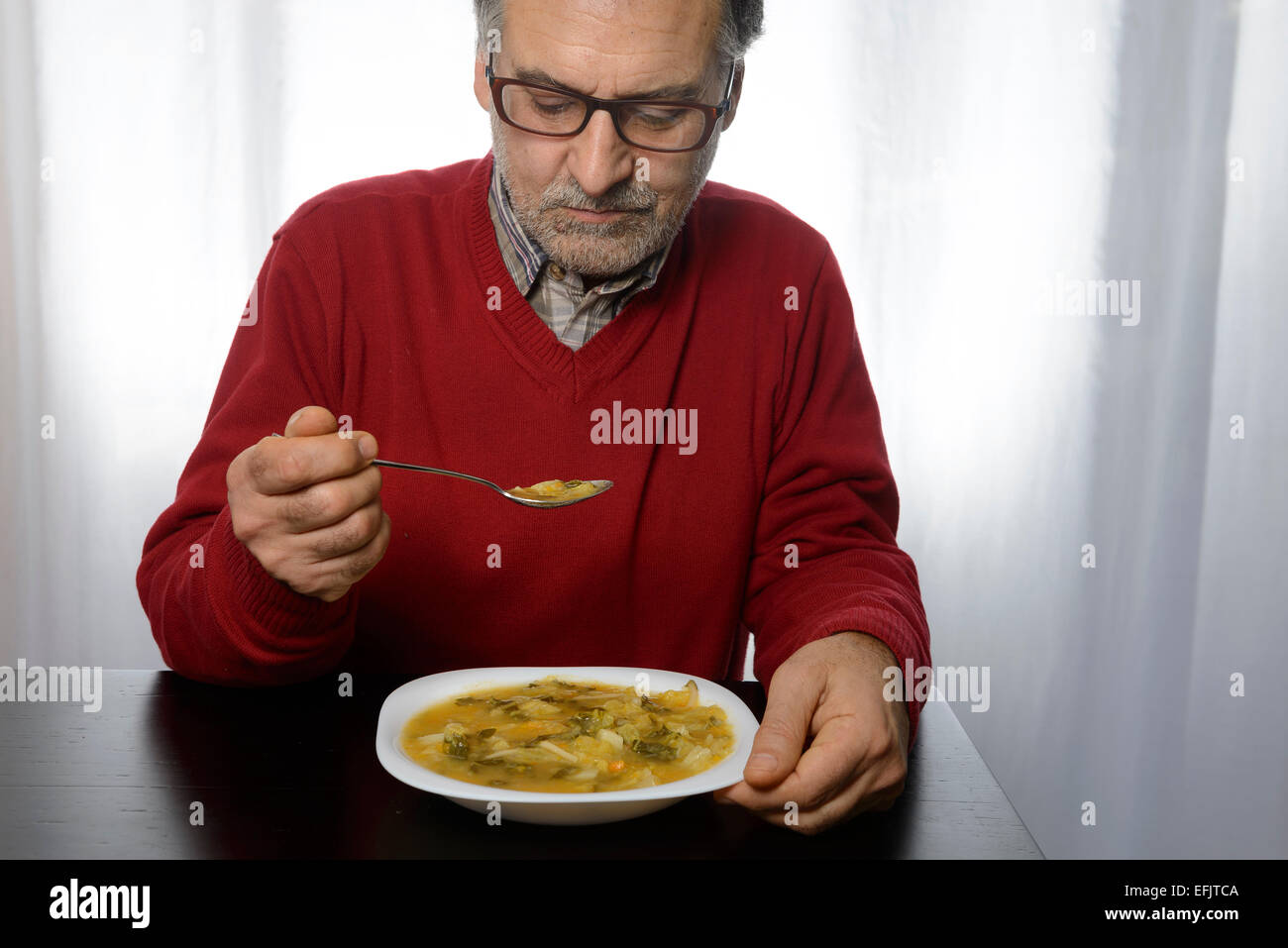 Uomo di mezza età di mangiare la minestra di verdura Foto Stock
