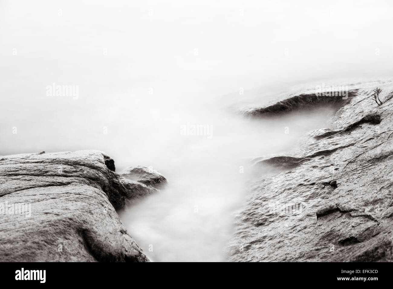 Natura tranquilla scena con una lunga esposizione di rocce scure e ancora acqua Foto Stock