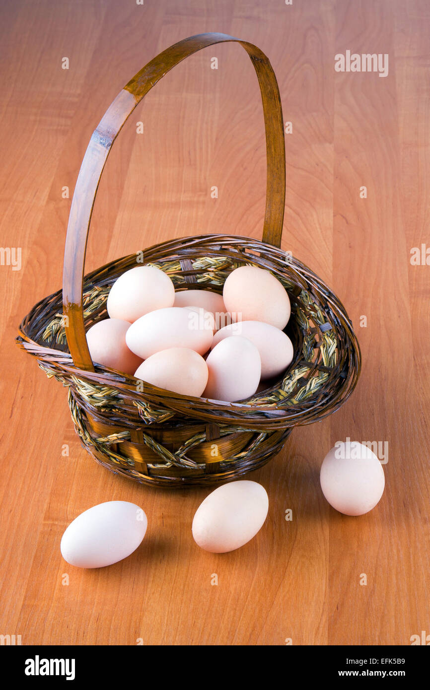 Le uova in un cesto su uno sfondo di legno Foto Stock