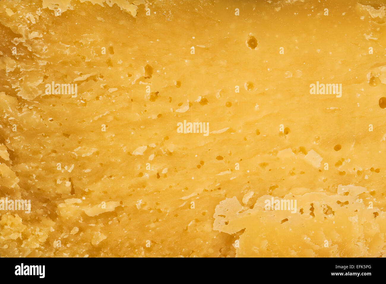 Il pezzo di formaggio giallo con fori come sfondo Foto Stock
