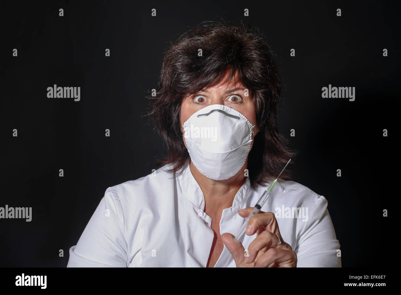 Medico donna con la siringa e la bocca maschera cercando spaventoso Foto Stock