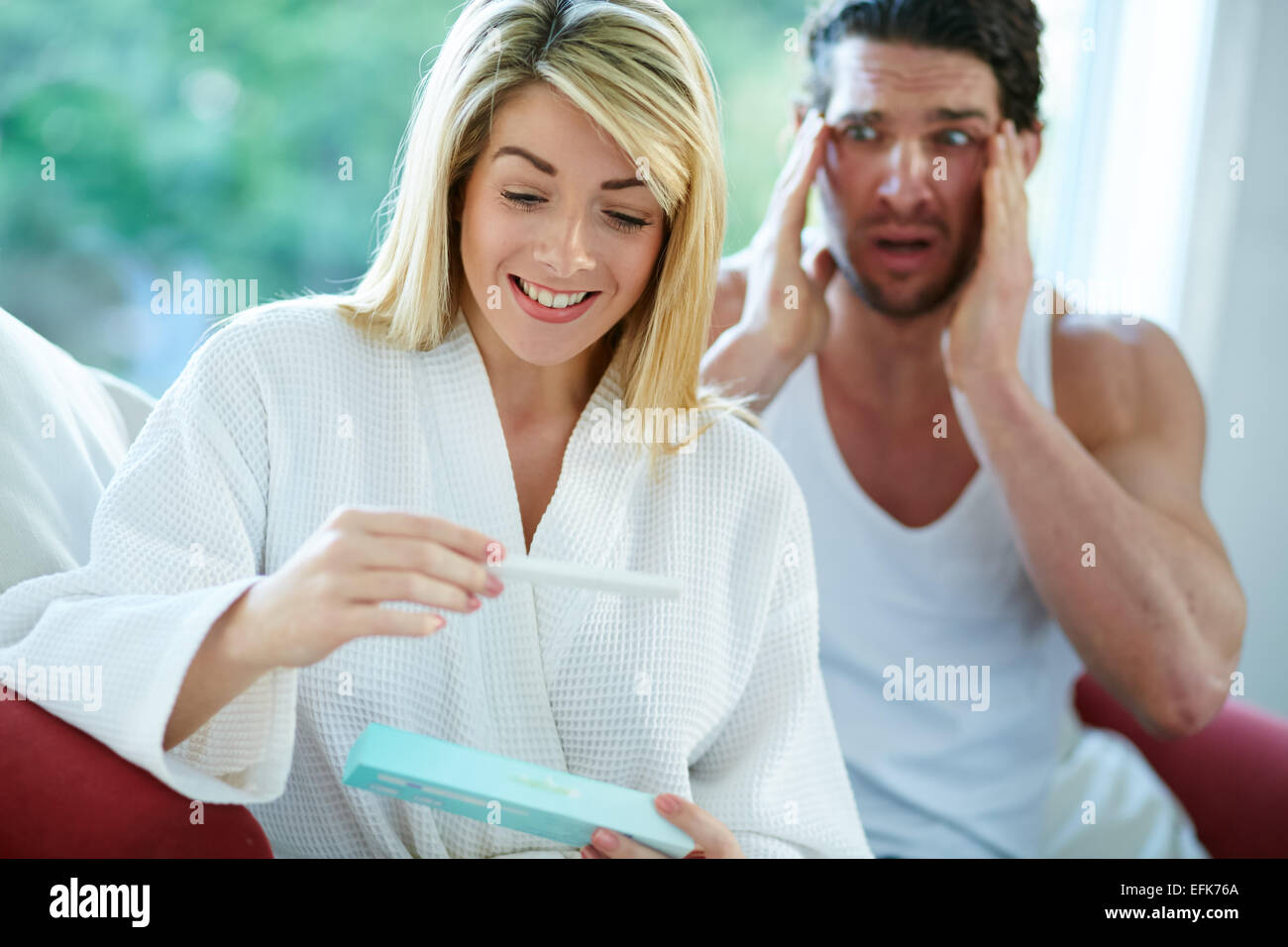 Ragazza felice di scoprire è incinta con sconvolto l uomo in background Foto Stock