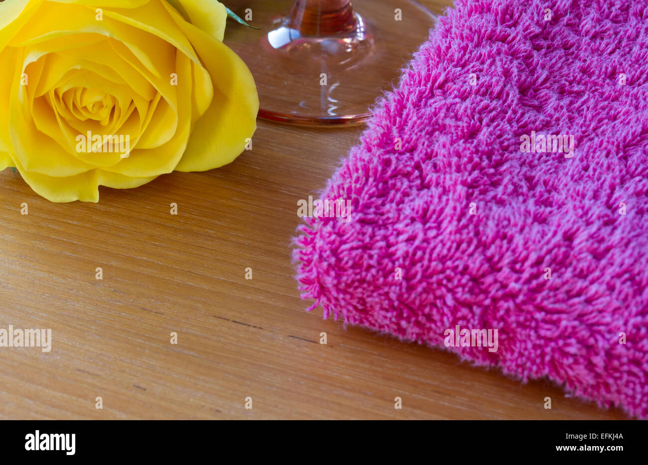 Rosa gialla con un bicchiere di vino e un asciugamano rosa Foto Stock